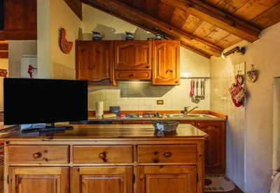 a kitchen with wooden cabinets and a monitor on a counter at Casa Mary in San Vito di Cadore