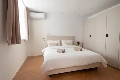 a white bedroom with a large white bed with two pillows at Apartment Merano Mitte in Merano