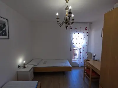a bedroom with a bed and a window with a chandelier at casa Daria in Predazzo