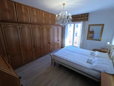 a bedroom with a bed with wooden cabinets and a chandelier at casa Daria in Predazzo