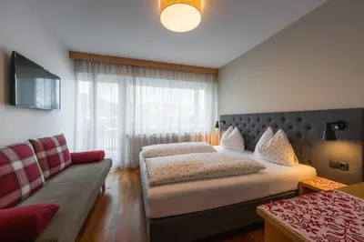 a hotel room with two beds and a couch at Haus Petra Mutschlechner in Riscone