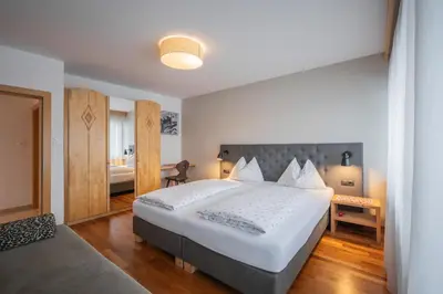 a bedroom with a large white bed and a bathroom at Haus Petra Mutschlechner in Riscone