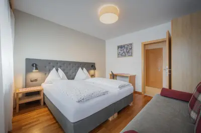 a bedroom with a large white bed and a chair at Haus Petra Mutschlechner in Riscone