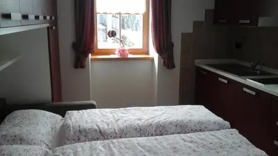 a small kitchen with a bed and a window at Cèsa Raggio di Sole in Arabba