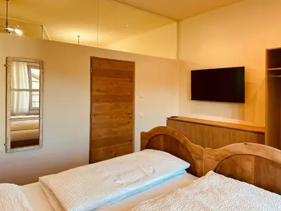 a bedroom with a bed and a flat screen tv at Zum Nussbaum in Termeno
