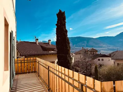 a wooden fence in front of a house with a tree at Zum Nussbaum in Termeno