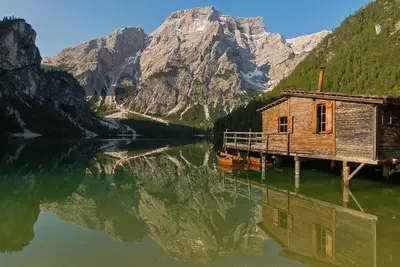 a house on a dock on a lake with a mountain at Haus Alpenheim in Braies