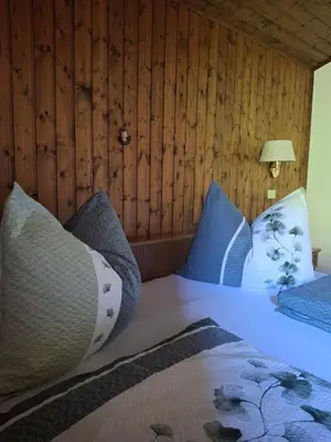 a bed with blue pillows in a room with wooden walls at Haus Alpenheim in Braies