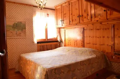 a bedroom with a bed with wooden cabinets and a window at Crepedel in Cortina dʼAmpezzo