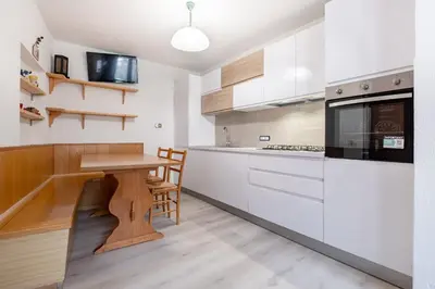 a kitchen with white cabinets and a wooden table at Casa Quinta by Go New Location in Predazzo