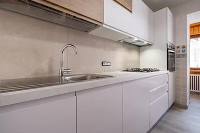 a kitchen with white cabinets and a sink at Casa Quinta by Go New Location in Predazzo