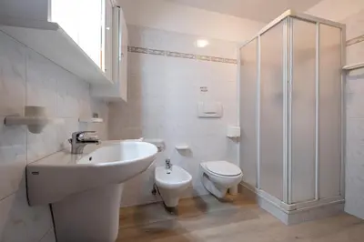 a white bathroom with a sink and a toilet at Casa Quinta by Go New Location in Predazzo