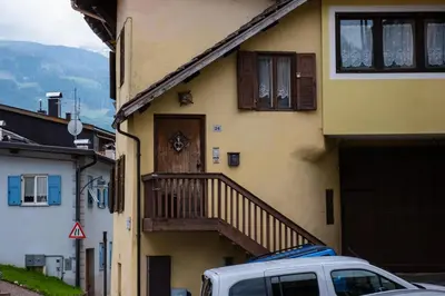 a yellow house with a wooden door and a balcony at Casa Quinta by Go New Location in Predazzo