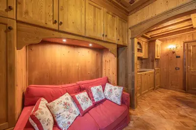 a living room with a red couch in a room with wooden walls at Casa Verocai, graziosi bilocali in centro a Cortina in Cortina dʼAmpezzo