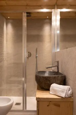 a bathroom with a stone sink and a shower at Casa Verocip, with panoramic balcony on Dolomites in Cortina dʼAmpezzo