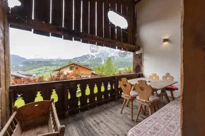 a balcony with a table and chairs and a mountain view at Casa Verocip, with panoramic balcony on Dolomites in Cortina dʼAmpezzo