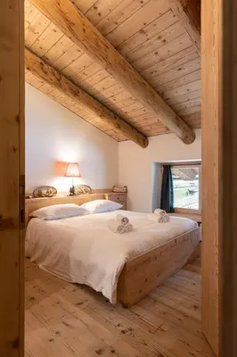 a bedroom with a large bed and a window at Casa Verocip, with panoramic balcony on Dolomites in Cortina dʼAmpezzo