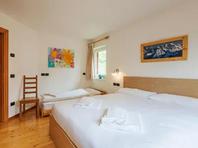 a bedroom with two beds and a chair at Apartment Erika by Interhome in Canazei