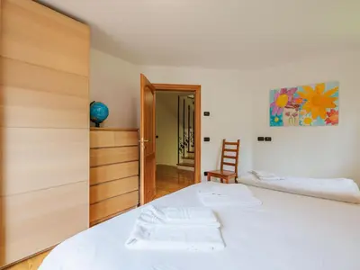 a bedroom with a white bed and a wooden closet at Apartment Erika by Interhome in Canazei