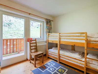 a bedroom with bunk beds and a chair and a window at Apartment Erika by Interhome in Canazei