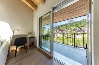 a bedroom with a bed and a desk and a balcony at Sass Maor - Caminetto in Transacqua