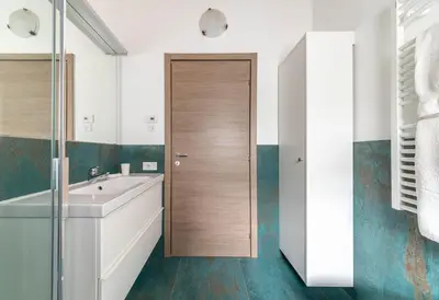 a bathroom with a sink and a wooden door at Pavione - Caminetto in Transacqua