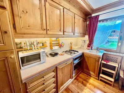a kitchen with wooden cabinets and a white microwave at Dolomiti quiet apartment with garden - San Vito in San Vito di Cadore
