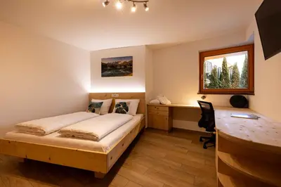 a bedroom with a bed and a desk and a window at Sirona Stay - Private Spa Retreat near Bolzano Dolomites - Romantic Stay with Sauna Whirlpool Garden Garage Free Bolzano Card in San Genesio Atesino