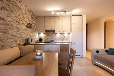 a kitchen and a living room with a wooden table at Sirona Stay - Private Spa Retreat near Bolzano Dolomites - Romantic Stay with Sauna Whirlpool Garden Garage Free Bolzano Card in San Genesio Atesino