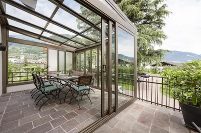 a conservatory with a table and chairs on a patio at Stammhaus Vetterer in Lana