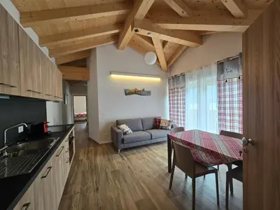 a kitchen and living room with a table and a couch at Miravalli Home in Gosaldo