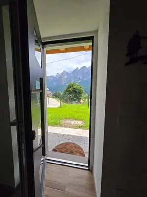 a house covered in snow with mountains in the background at Miravalli Home in Gosaldo