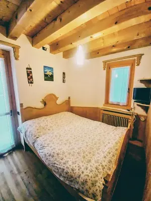 a bedroom with a bed in a room with wooden ceilings at Beautiful apartment in Zoldo Alto Dolomites in Pianaz