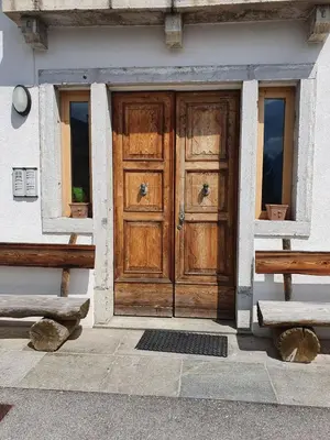 a wooden door of a building with two benches at Beautiful apartment in Zoldo Alto Dolomites in Pianaz