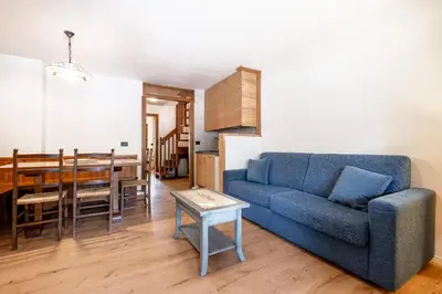 a living room with a blue couch and a table at Un respiro nel bosco - Residence Cèsa Da Mont in Penia
