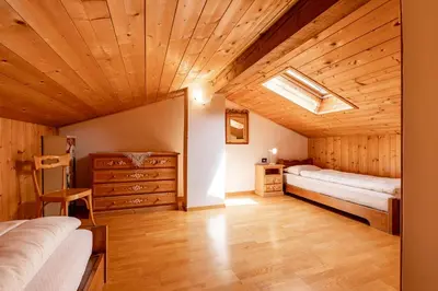 a bedroom with two beds and a wooden ceiling at Un respiro nel bosco - Residence Cèsa Da Mont in Penia
