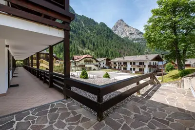a building with a balcony with a view of a mountain at Un respiro nel bosco - Residence Cèsa Da Mont in Penia