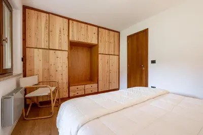 a bedroom with a white bed and wooden cabinets at Un respiro nel bosco - Residence Cèsa Da Mont in Penia