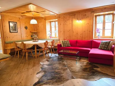 a living room with a red couch and a table at Essenze di Bosco - Alpine Stay Apartments in Predazzo