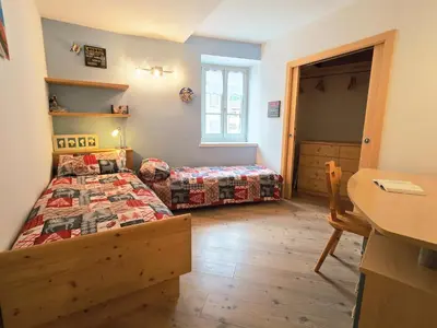 a bedroom with two beds and a table and a desk at Essenze di Bosco - Alpine Stay Apartments in Predazzo
