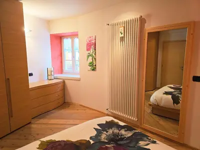 a bedroom with a bed and a dresser and a mirror at Essenze di Bosco - Alpine Stay Apartments in Predazzo