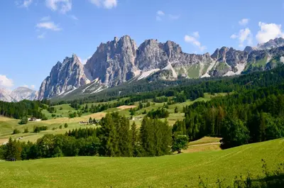 a green field with mountains in the background at Cozy flat in amazing central location in Cortina dʼAmpezzo
