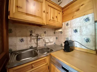 a kitchen with a stainless steel sink and wooden cabinets at Cozy flat in amazing central location in Cortina dʼAmpezzo