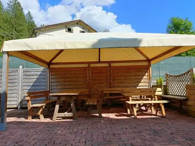 a picnic shelter with a table and benches at La Casetta in San Vito di Cadore