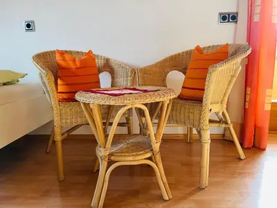 two wicker chairs and a table with orange pillows at Apartment Oberhauserhof in Falzes