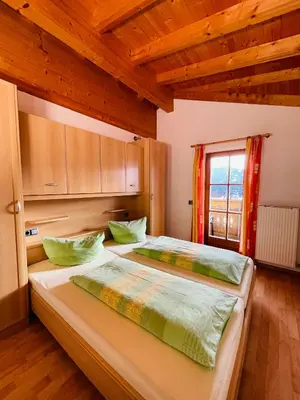 two beds in a room with wooden ceilings and a window at Apartment Oberhauserhof in Falzes