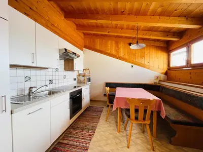 a kitchen with a table and a kitchen with white cabinets at Apartment Oberhauserhof in Falzes