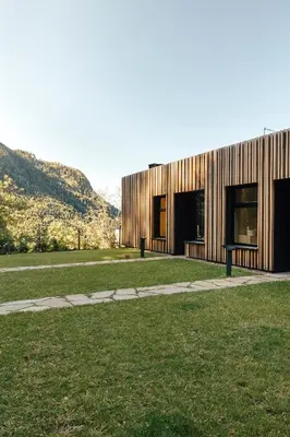 a wooden building on a field with mountains in the background at Hochegg Hideaway in Laives