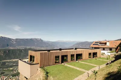 a house on a hill with mountains in the background at Hochegg Hideaway in Laives