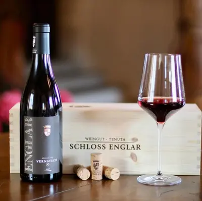 a bottle of red wine next to a glass at Schloss Englar in Appiano sulla Strada del Vino
